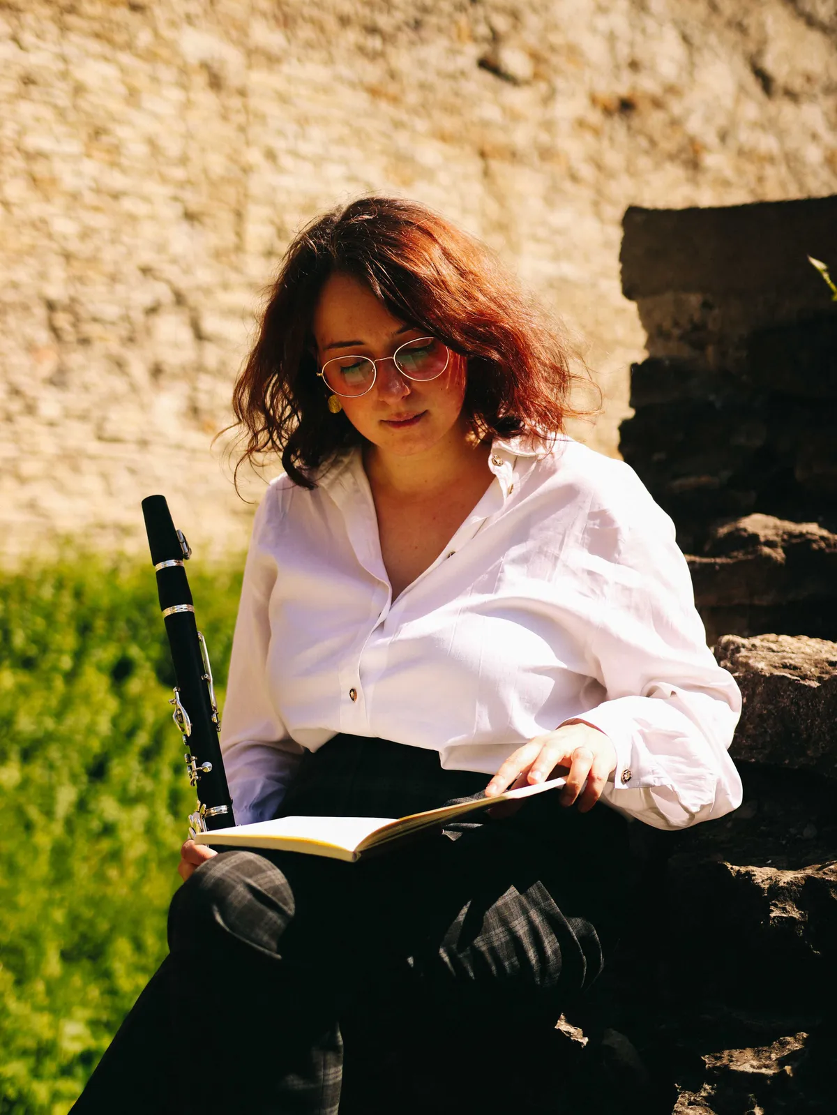 Vittoria Ecclesia seduta su una scalinata di pietra, con il clarinetto accanto, legge un quaderno
